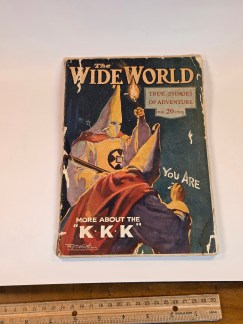 A vintage magazine cover titled "THE WIDE WORLD," showing two hooded Klansmen and the words "MORE ABOUT THE K.K.K."