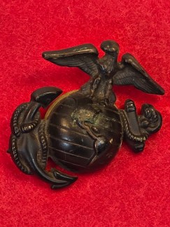: A collection of original WWII-era US Marine Corps black oxidized Eagle, Globe, and Anchor emblems, some with screw-post backs.