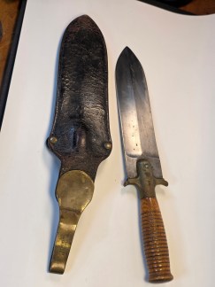 A U.S. Springfield M1880 sheath knife and its scabbard. The knife has a wide blade, a wooden handle, and a brass guard stamped "U.S. SPRINGFIELD.