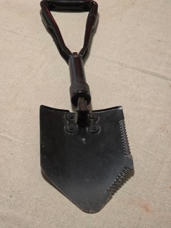 Black US Military folding entrenching tool (E-Tool) displayed next to its new MOLLE II UCP camouflage carrier pouch in plastic.