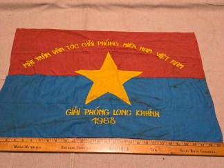 Authentic Viet Cong NLF banner in red, blue, and yellow with embroidered Vietnamese script commemorating the Long Khánh Liberation in 1968.