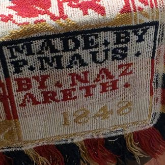 Close up photo of 1848 P Maus coverlet made in Nazareth PA showing red blue and tan woven pattern with maker date block