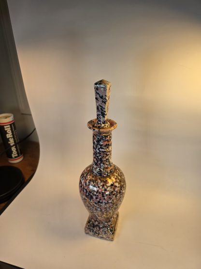 Tall ceramic Mid-Century Modern decanter in a pink, black, white, and metallic gold speckled "confetti" pattern with its original squared stopper.