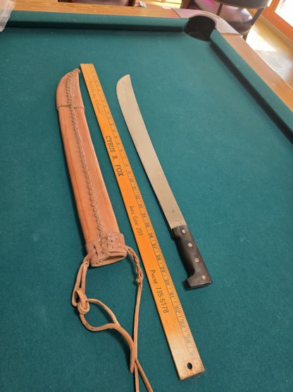 Full-length 28 3/4 inch Collins Legitimus military machete with black handle and original brown leather scabbard on a neutral background.