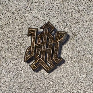 Close-up of a metal WW2 German LSSAH shoulder board cipher with the interlaced letters LAH and mounting prongs on the back.