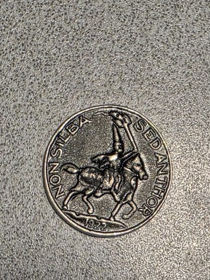 Front and back view of a 1922 metal token showing a hooded horseman and a long inscription on the reverse.