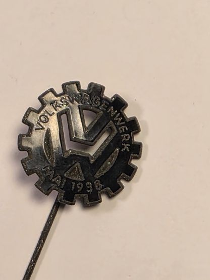 (Alt Text): Metal stickpin featuring a gear-shaped logo with "VOLKSWAGENWERK MAI 1938" and the VW monogram.
